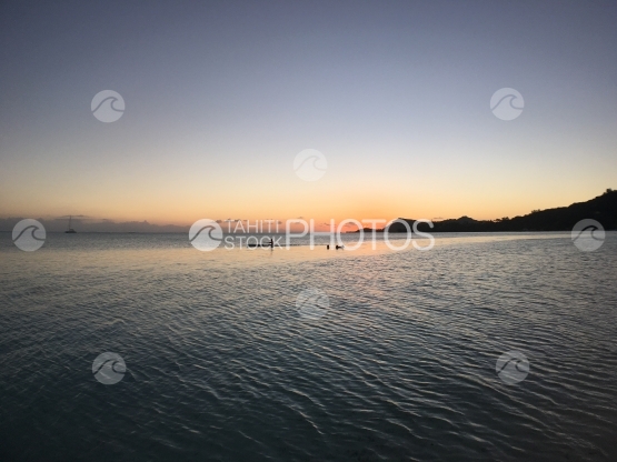Canoe driving through sunset scenery at Matira beach, Bora Bora