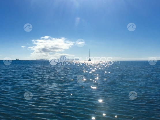 Catamaran anchored in the lagoon of Tahaa, Bora Bora in the background