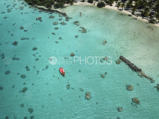 Toau, aerial shot of a red motot boat in the lagoon
