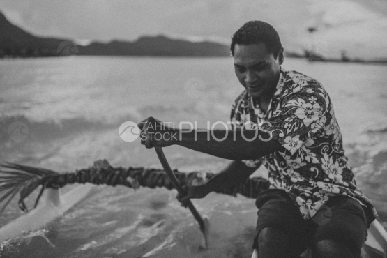 BORA BORA, TRADITIONAL POLYNESIAN man paddling on his  OUTRIGGER canoe