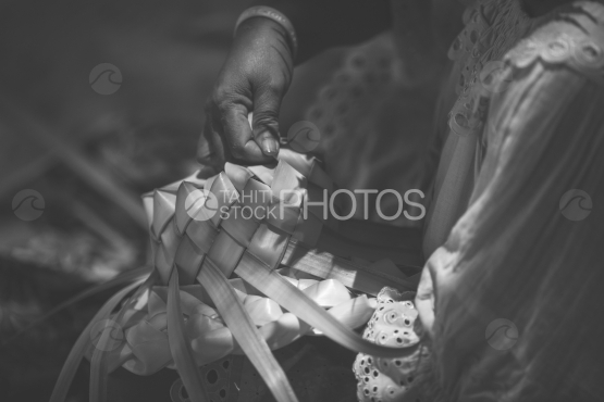 Polynesian woman braiding a hat with coconut tree leaf, Bora Bora