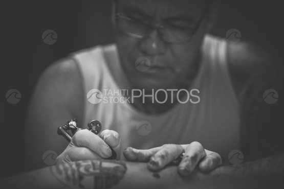 Bora Bora, tattoo artist working on arm of polynesian man